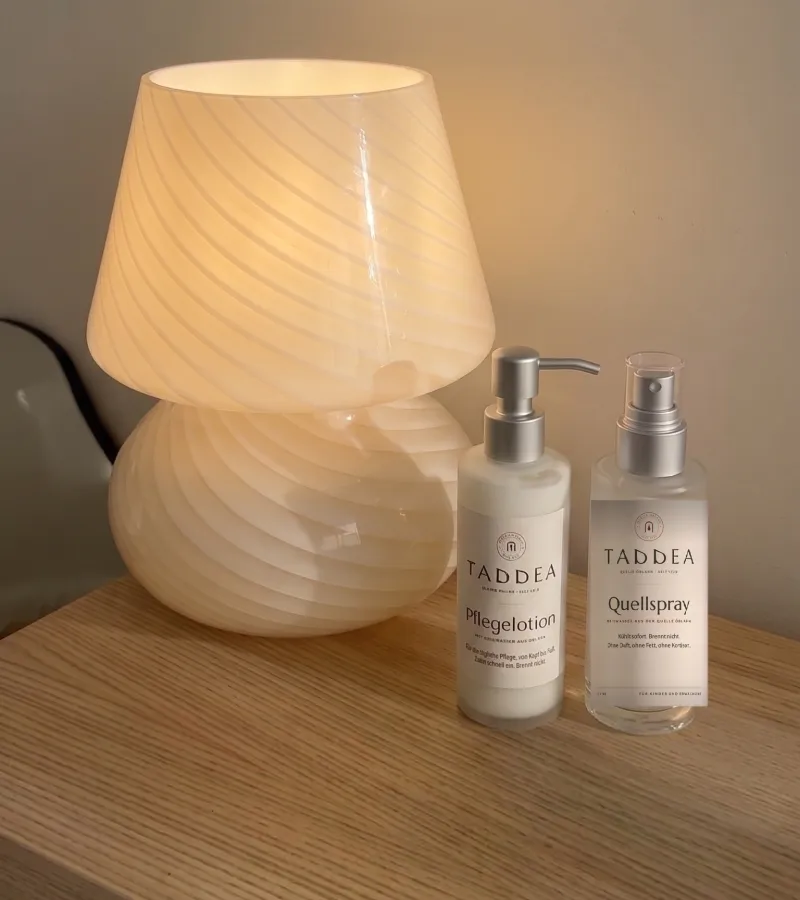Quellspray und Pflegelotion auf einem Nachttisch neben einer Lampe